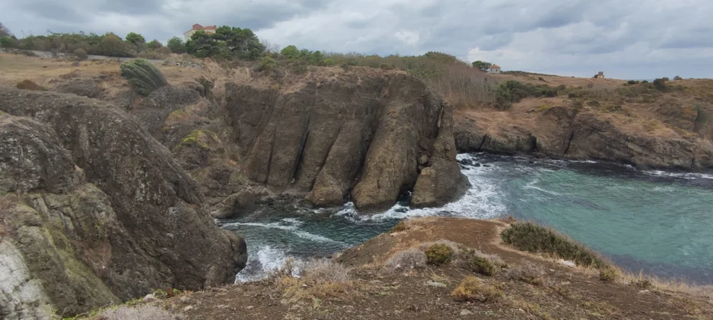 Bulutlu havada kayalık kıyı ve turkuaz denizin göründüğü manzara fotoğrafı.