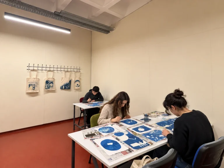 Katılımcıların mavi-beyaz cyanotype baskıları çalışma masasında incelediği temsili uygulama görseli.